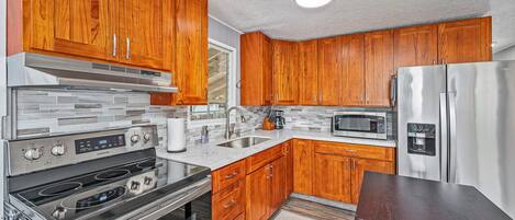 Una cocina con armarios de madera, electrodomésticos de acero inoxidable y salpicadero de azulejos.