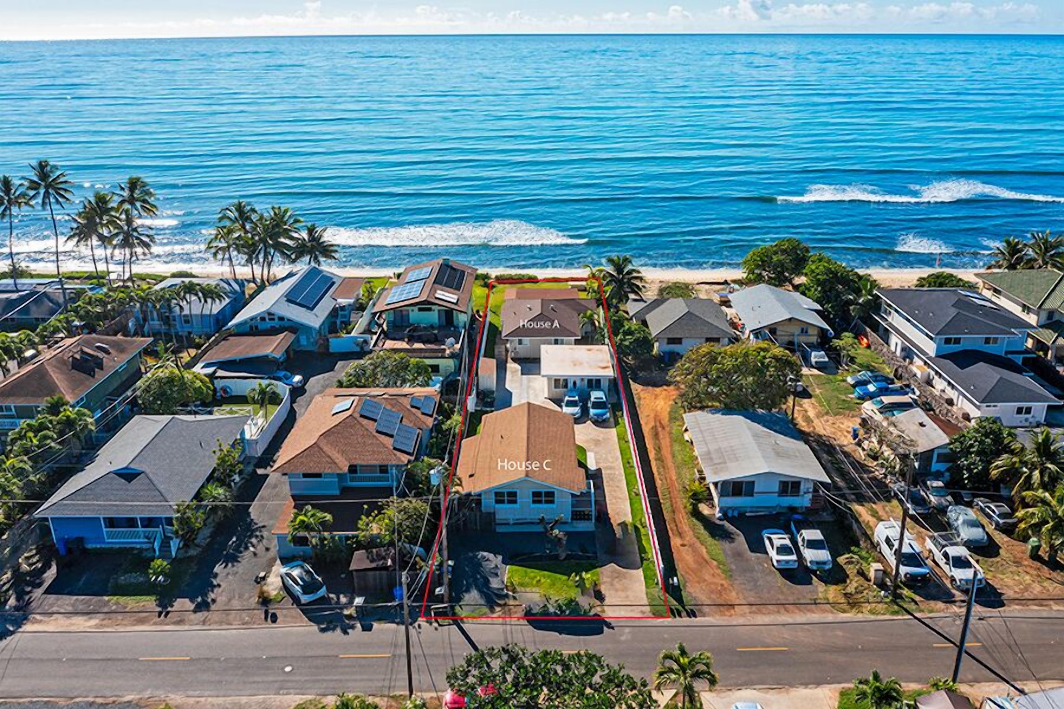 A coastal residential area with houses, a road, and the ocean.