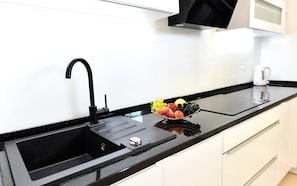 A modern kitchen with a black countertop, a sink, and a fruit bowl.