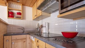A modern kitchen with wooden cabinets, a stainless steel range hood, a built-in oven, and a red bowl on the counter. - Bel Apt Near The Slopes Argentiere (Chamonix-Mont-Blanc)