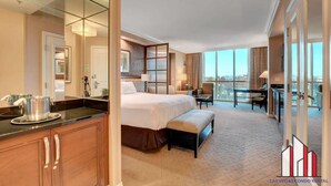 Une chambre d’hôtel avec un grand lit, un bureau, une chaise, une table à manger et un balcon avec vue.