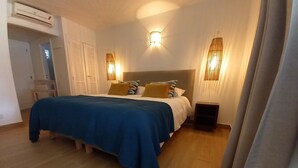 A bedroom with a bed, bedside tables, a nightstand, and a wall-mounted air conditioner. - beautiful studio in st martin (Saint Martin)