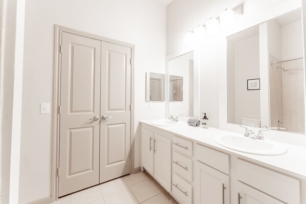 A modern bathroom with two sinks, a large mirror, and a shower area.