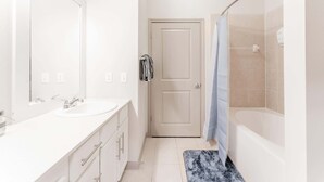 Une salle de bain moderne avec un double vasque, une douche et une porte donnant sur une autre pièce.