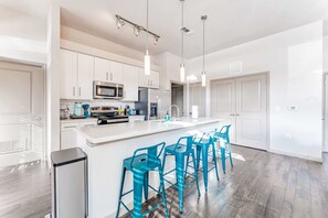 A modern kitchen with white cabinets, stainless steel appliances, and a central island with bar stools.