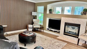 Un salon avec une cheminée, un téléviseur à écran plat et un mur à rayures.