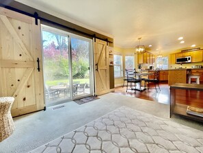 A spacious kitchen with wooden cabinets, a dining area with a table and chairs, and a sliding glass door leading to a garden.