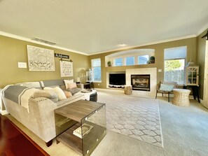 A living room with a sofa, TV, fireplace, and decorative wall art.