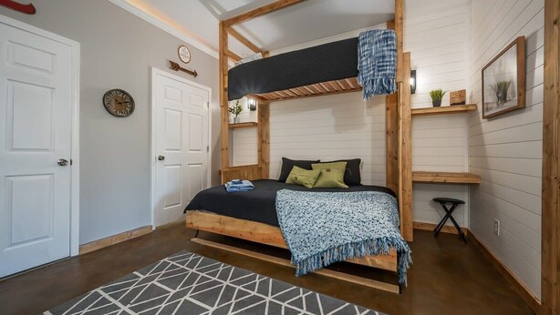 A bedroom with a bunk bed, a bedside table, a clock, and a window with blinds. - Lakeshore Retreat with Lake Lanier views & hot tub (Landrum)