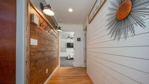 A hallway with wooden paneling on one side and white paneling on the other, leading to a room with a bed.