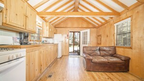 A wooden cabin interior with a kitchen, a dining area, and a living room with a leather couch. - The Colorado Spruce Cabin #15 (Bayfield)