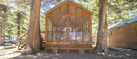 Een houten chalet met schuin dak, omgeven door bomen.