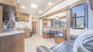 Un intérieur de camping-car compact comprenant un coin cuisine, un espace repas et un coin salon avec vue.