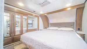 Une chambre à coucher avec un grand lit, une armoire et un miroir.