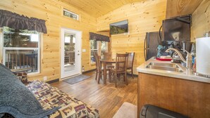 A cozy cabin interior with a wooden interior, a dining area, and a kitchen with a sink and stove. - The Twilight Cabin #4 (Bayfield)