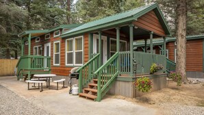 A cabin with a porch, outdoor seating, and a gas tank. - The Wolf Den Cabin #13 (Bayfield)
