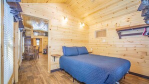 A cozy wooden cabin bedroom with a bed, a small table, and a window. - The Wolf Den Cabin #13 (Bayfield)