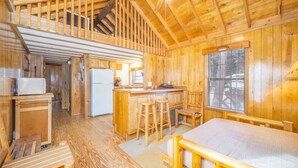 A wooden cabin interior with a kitchen, dining area, and a loft bedroom. - The Weminuche Cabin #80 (Bayfield)
