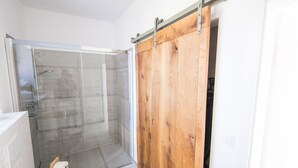 Un baño moderno con ducha, inodoro y puerta corredera de madera.