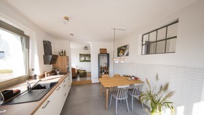Una cocina moderna con una mesa y sillas de madera, horno empotrado y un ventanal grande.