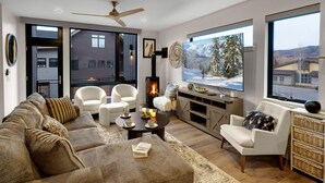 Una sala de estar moderna con chimenea, asientos cómodos y ventanas amplias que ofrecen vistas al exterior.