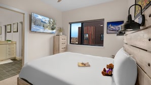 Un dormitorio con cama, cómoda, televisor y ventana con vista a un edificio.