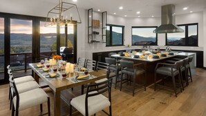 A modern kitchen with a large island, dining area, and large windows offering scenic views.