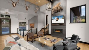 A modern living room with a fireplace, a television, and a large window with a view of trees.
