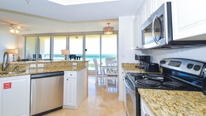 A modern kitchen with granite countertops, stainless steel appliances, and a view to the outside. - 5th Floor 3 Bedroom Condo with Semi-Private Elevator (Destin)