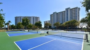 Un court de tennis avec un filet, entouré d’arbres et de bâtiments.