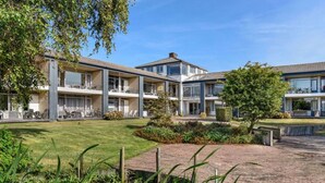 Un hôtel moderne à plusieurs étages, doté d’une terrasse et de jardins bien entretenus.