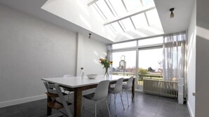 Un espace de repas moderne, avec une table et des chaises, une verrière et une vue sur l’extérieur.