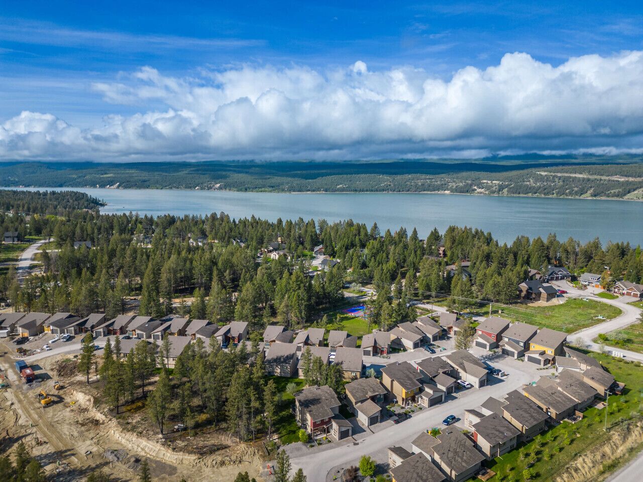 Vista aérea de una zona residencial con casas, una carretera y una masa de agua al fondo.
