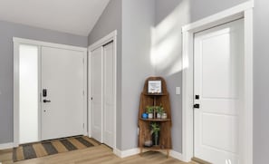 Um corredor com três portas brancas, uma prateleira de madeira com plantas e um tapete de entrada.
