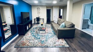 A modern living room with a large mirror, a sofa, a coffee table, and a patterned rug. - Cozy Beautiful 2BD Apt in Center City (Philadelphia)