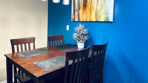 A dining area with a wooden table, four chairs, a potted plant, and a blue accent wall. - Cozy Beautiful 2BD Apt in Center City (Philadelphia)