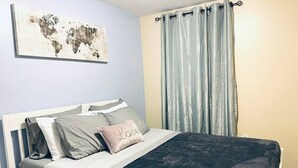 A neatly made bed with a dark bedspread, light-colored pillows, and a decorative pillow with the word "Love". - Cozy Beautiful 2BD Apt in Center City (Philadelphia)