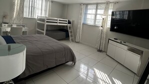 A bedroom with a bed, a desk, a TV, and a cabinet. - Hollywood beach apartment on the beach the biggest in the building all new  (Hollywood)