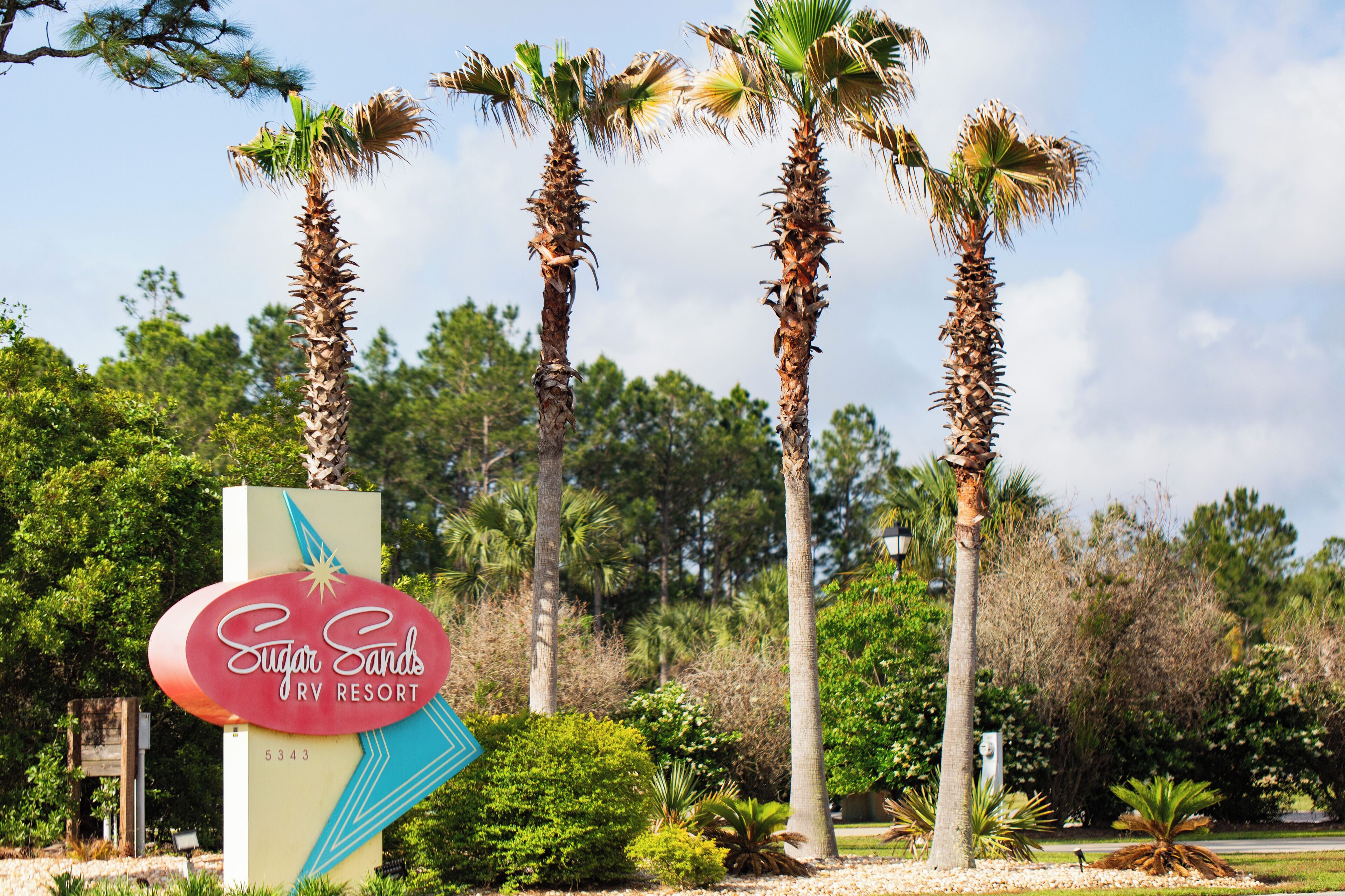 A sign for Sugar Sands Dry Resort with palm trees in the background.