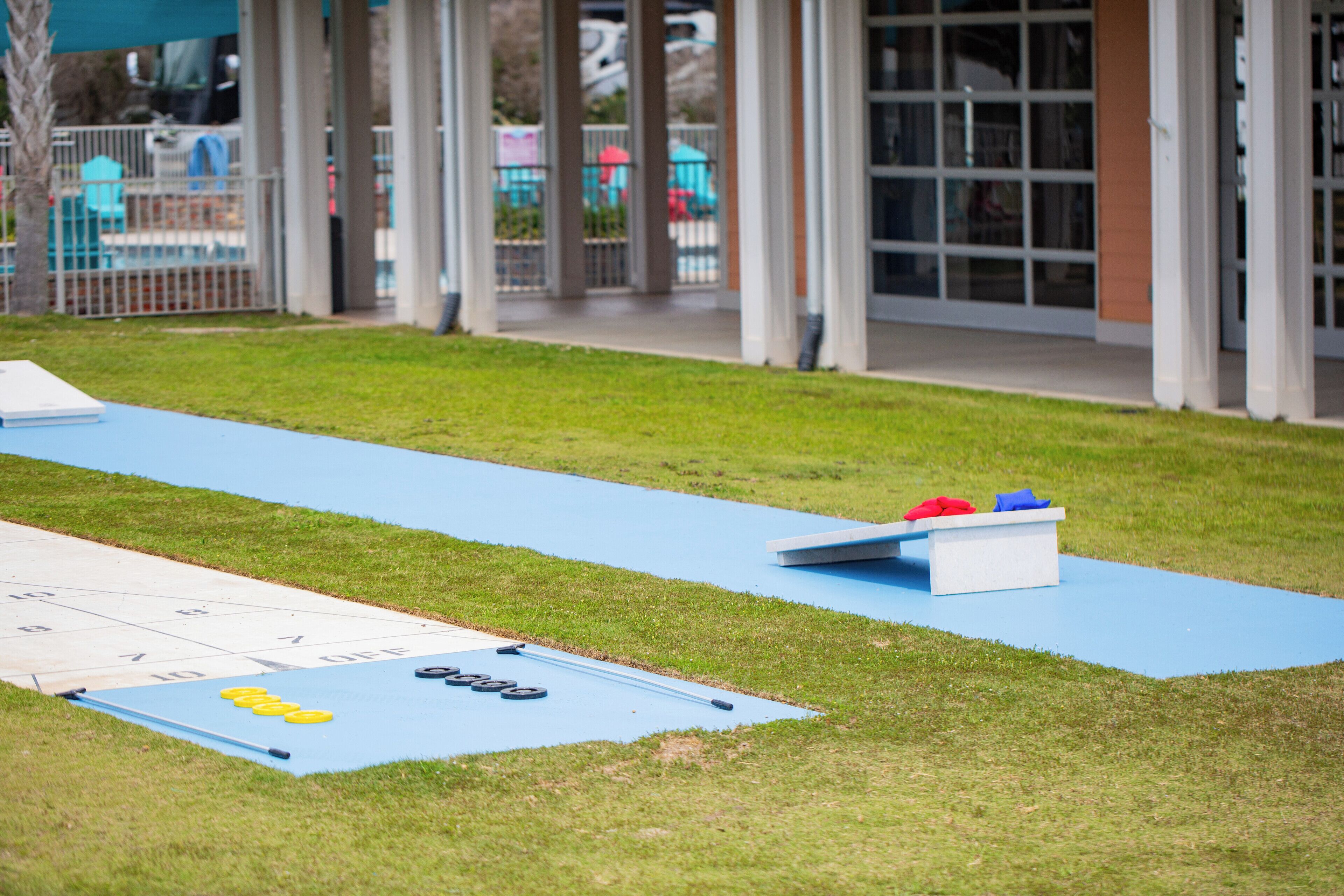 A shuffleboard table and a bocce court in an outdoor area with a building in the background.