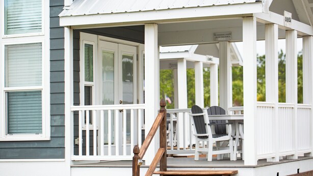 A covered porch with a table and chairs, a wooden staircase, and a sign prohibiting smoking on the porch. - Sugar Sands RV Resort (Gulf Shores)