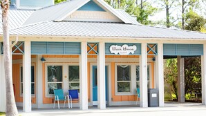 A building with a sign reading "Wash House NORTH" and a covered outdoor seating area with chairs. - Sugar Sands RV Resort (Gulf Shores)