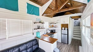 A compact kitchen with white cabinetry, a black leather bench, and a wooden ceiling. - Sugar Sands RV Resort (Gulf Shores)