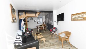 A compact living space with a sofa, chairs, a dining area, and a TV. - Gîte bord de mer "A l'abordage" Exceptional view (Fécamp)