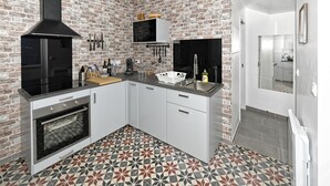 A modern kitchen with a brick wall backsplash, a built-in oven, and a patterned tile floor. - Gîte bord de mer "A l'abordage" Exceptional view (Fécamp)