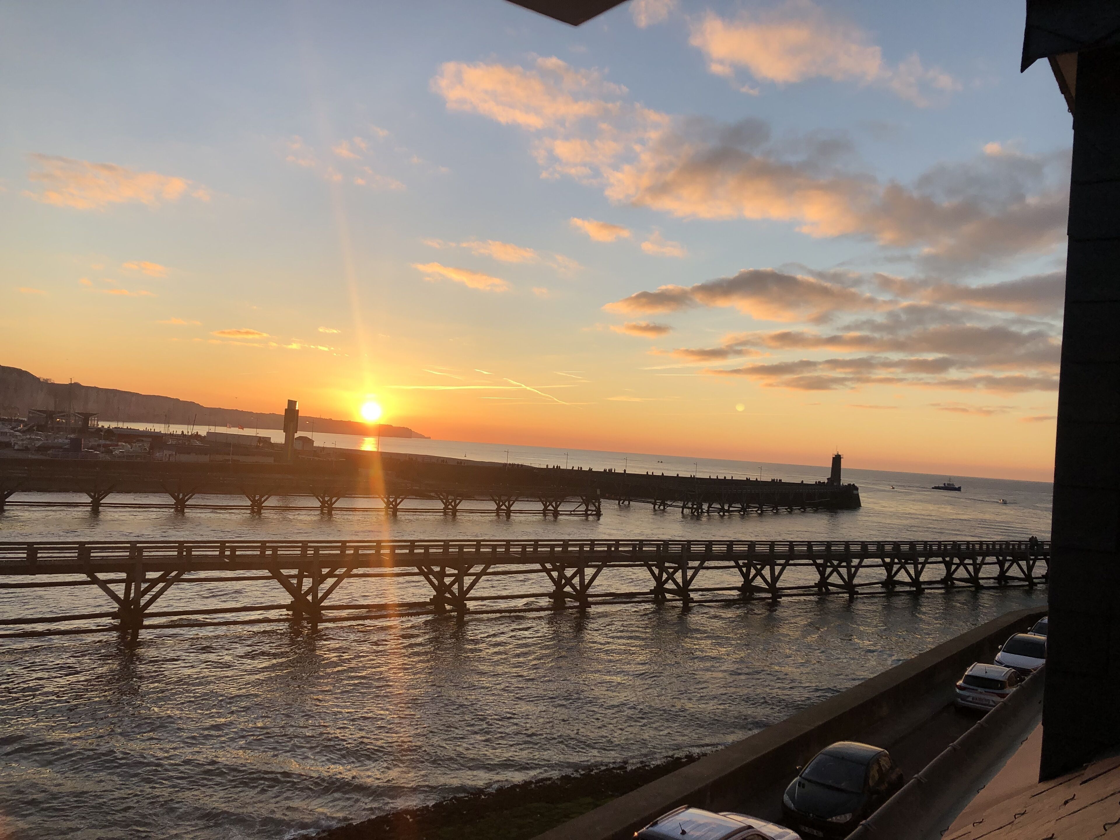 En solnedgång över en strandpromenad med en brygga som sträcker sig ut i vattnet.