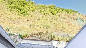 A patio area with a table and chairs, a view of a hillside, and a garage door with labels. - Gîte bord de mer "A l'abordage" Exceptional view (Fécamp)
