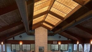 An indoor swimming pool with a high ceiling and skylights, surrounded by lounge chairs and a stone pillar. - Beach Front Property with Stunning  Ocean Front View in the Ocean Dunes Resort (Kure Beach)