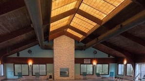 An indoor swimming pool with a stone pillar, wooden beams, and a tiled floor.