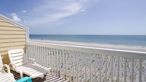 A beach view from a balcony with white chairs and a wooden deck. - Beach Front Property with Stunning  Ocean Front View in the Ocean Dunes Resort (Kure Beach)
